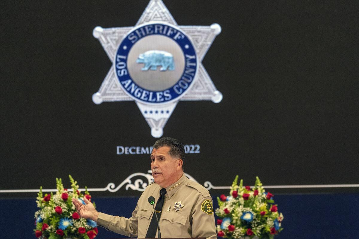 A man in uniform speaks under an image of a giant sheriff's badge.