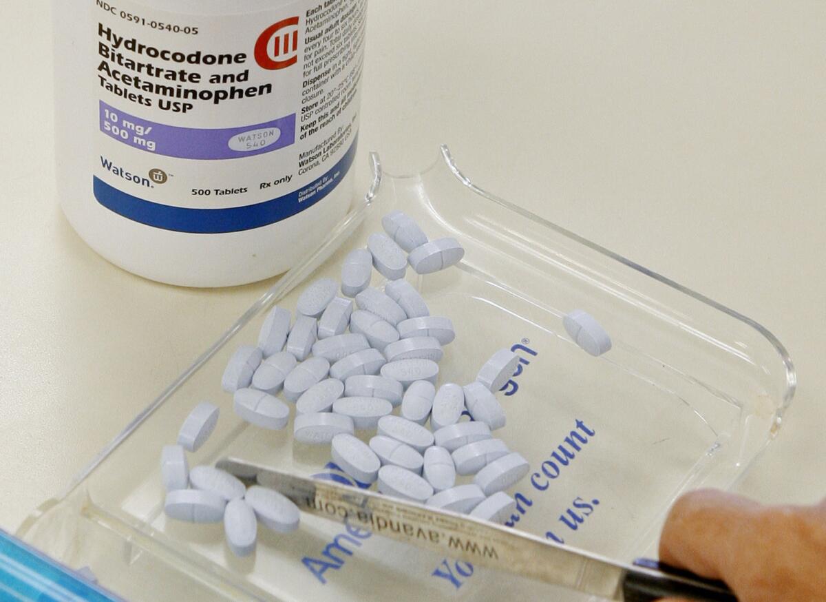 A pharmacy technician counts pain pills