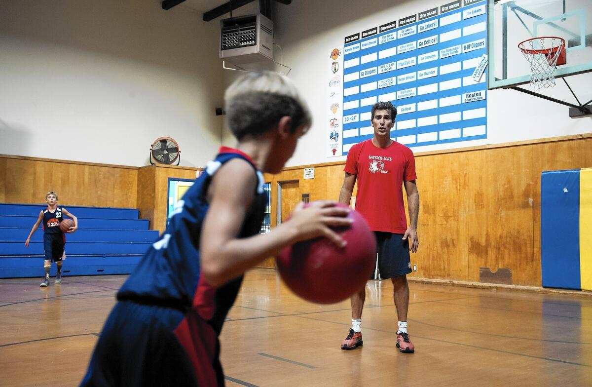 Dylan Rigdon coaches his sons Joaquin, center, and Eamon, left, at the Boys & Girls Club of the Harbor Area in Costa Mesa.