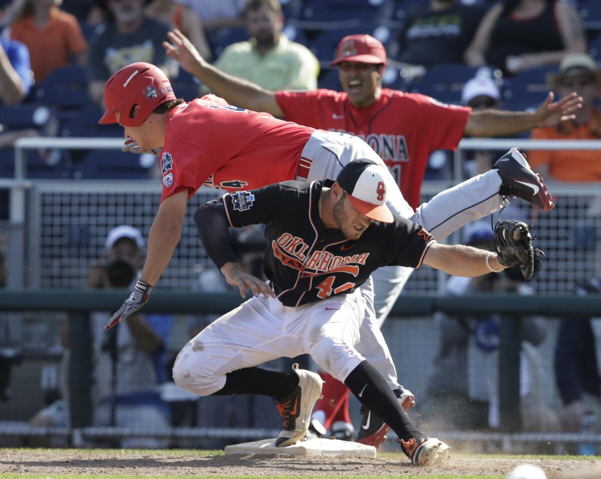 Arizona's Justin Behnke (4) is safe at first base after colliding with Oklahoma State first baseman Andrew Rosa (44) on a bunt in the ninth inning.