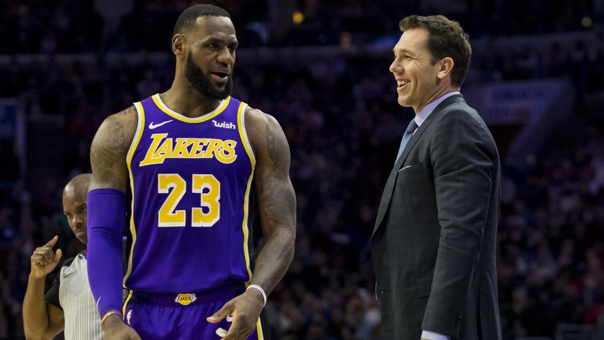 Lakers' head coach Luke Walton, right, talks things over with LeBron James, left, during the first half against the Philadelphia 76ers on Sunday.