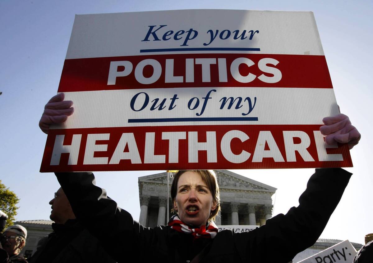 Seen here in March 2012, a protester who opposes President Obama's healthcare reform law demonstrates outside the Supreme Court as the justices hear oral arguments on the law. On Tuesday, the first open enrollment period in the state insurance exchanges will begin.