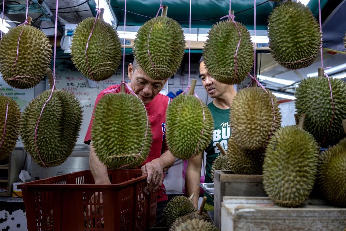 A customer, right, orders some durians at a roadside stall during the Durian Festival in Georgetown, Malaysia. (Suzanne Lee / For The Times)