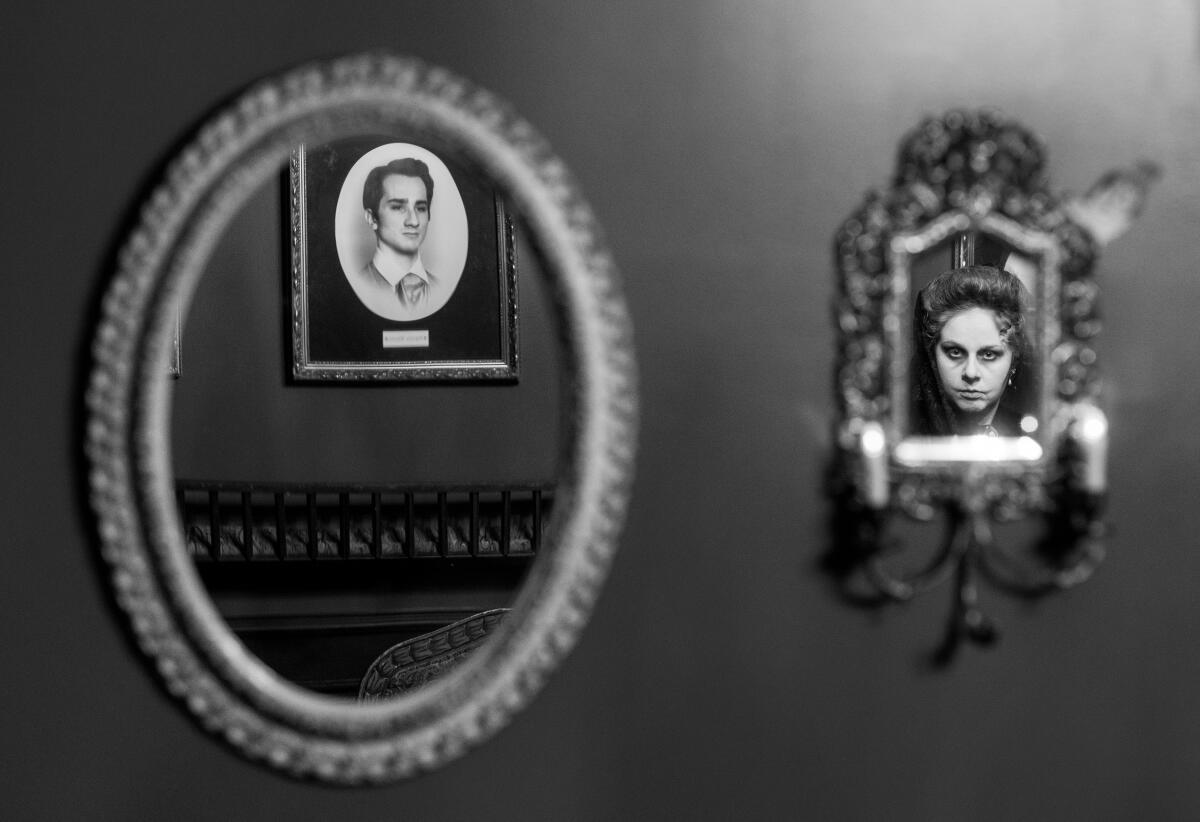 A reflection in a mirror of a portrait hung on the wall, left, and the reflection of a woman in a mirror on the right