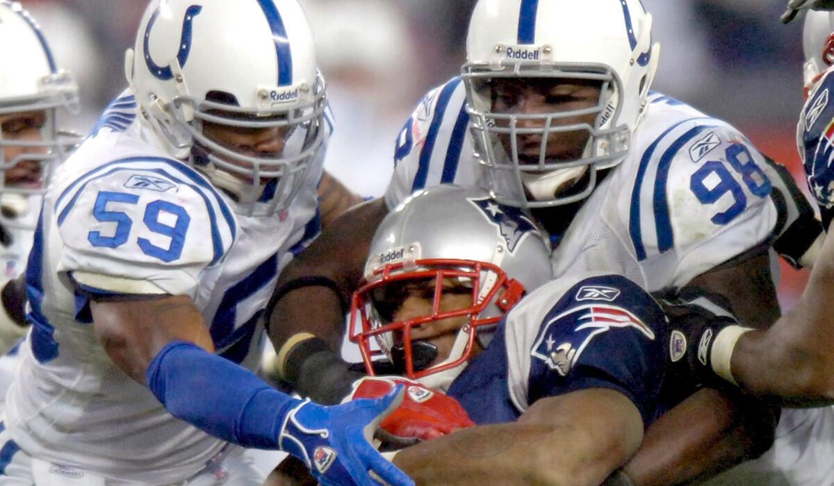Colts defensive end Robert Mathis (98) helps bring down Patriots running back Corey Dillon.