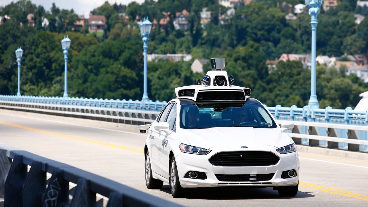 Uber employees test a self-driving Ford Fusion hybrid car in Pittsburgh on Aug. 18.