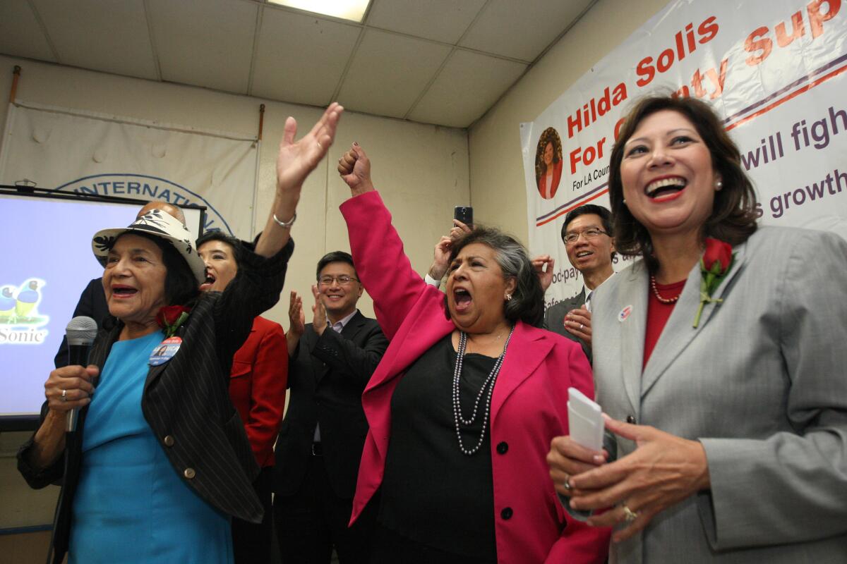 Gloria Molina, dressed in a red blazer, raises her fist during an election night party in 2014.