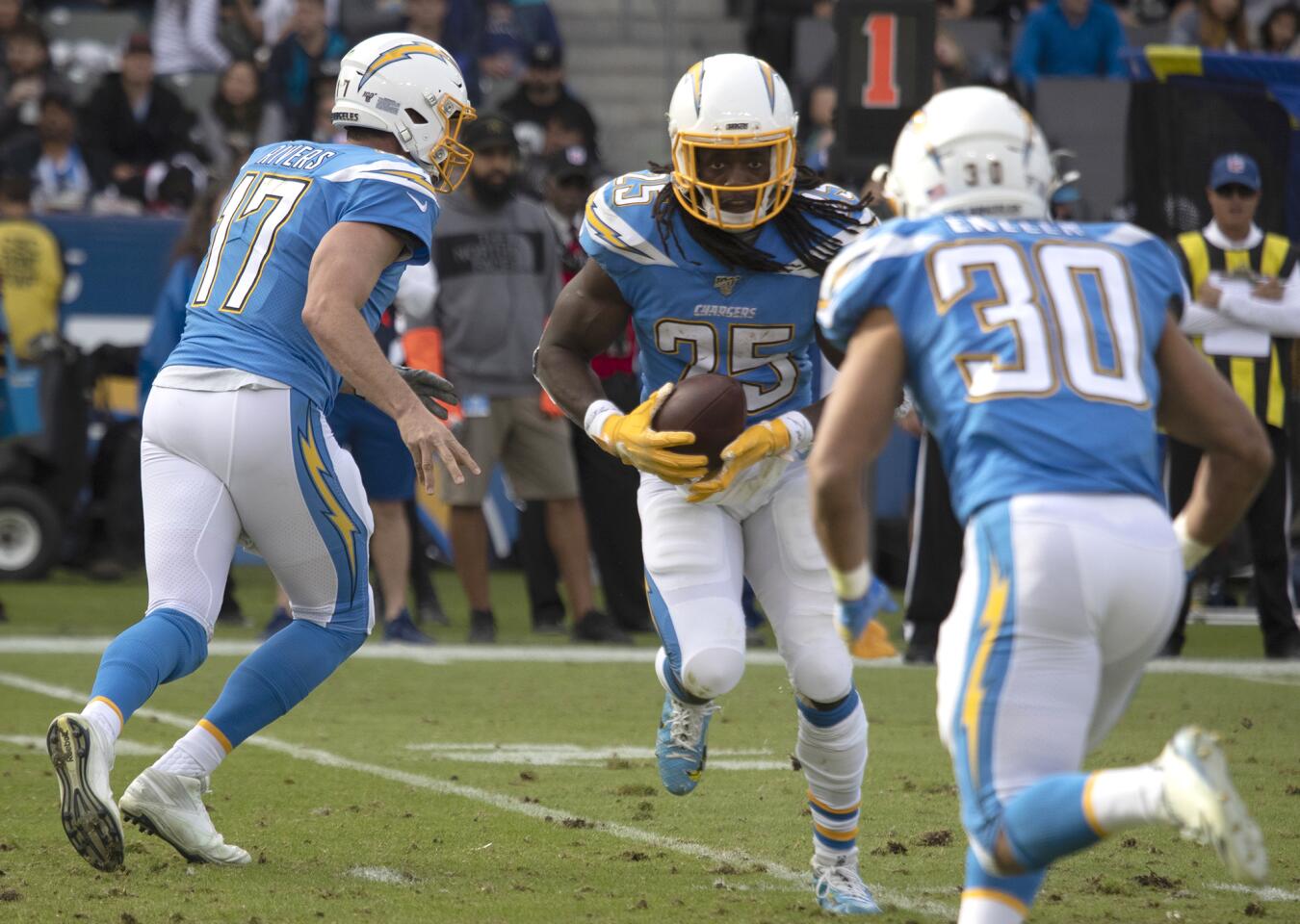 Chargers running back Melvin Gordon, center, looks to handoff to teammate Austin Ekeler (30) on a reverse against Oakland Raiders.