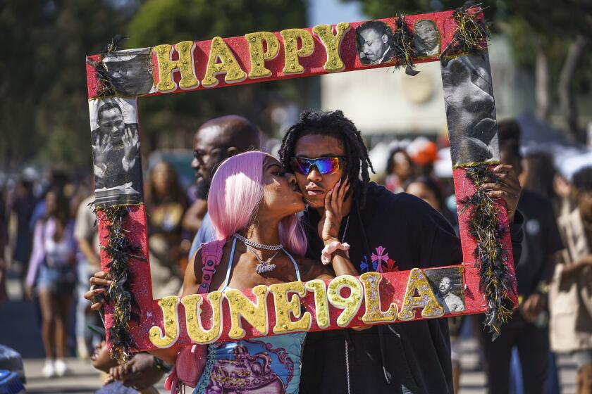 Daisa Chantel kisses Anthony Beltran as they take a picture to celebrate Juneteenth at Leimert Park in Los Angeles on Saturday, June 18, 2022. (AP Photo/Damian Dovarganes)