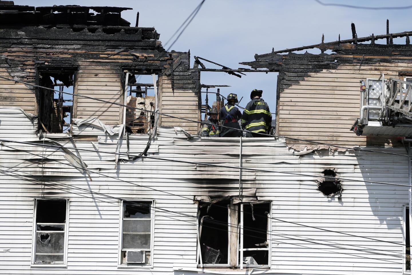 Firefighters work on the top floor of a burned Lowell, Mass., apartment building where officials said seven people, including three children, died in a fast-moving blaze. The building did not have a sprinkler system, said State Fire Marshal Stephen Coan.
