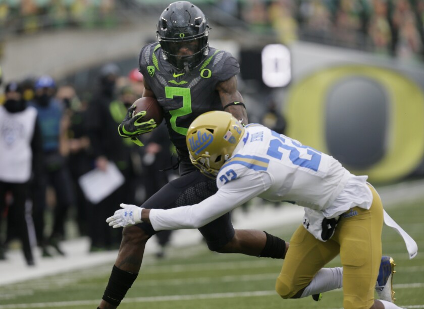 Oregon's Devon Williams runs as UCLA's Obi Eboh reaches out for a tackle.