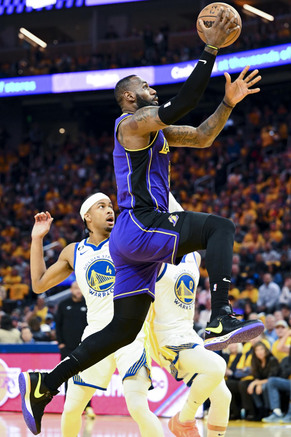 Lakers forward LeBron James elevates for a layup past Warriors guard Moses Moody.