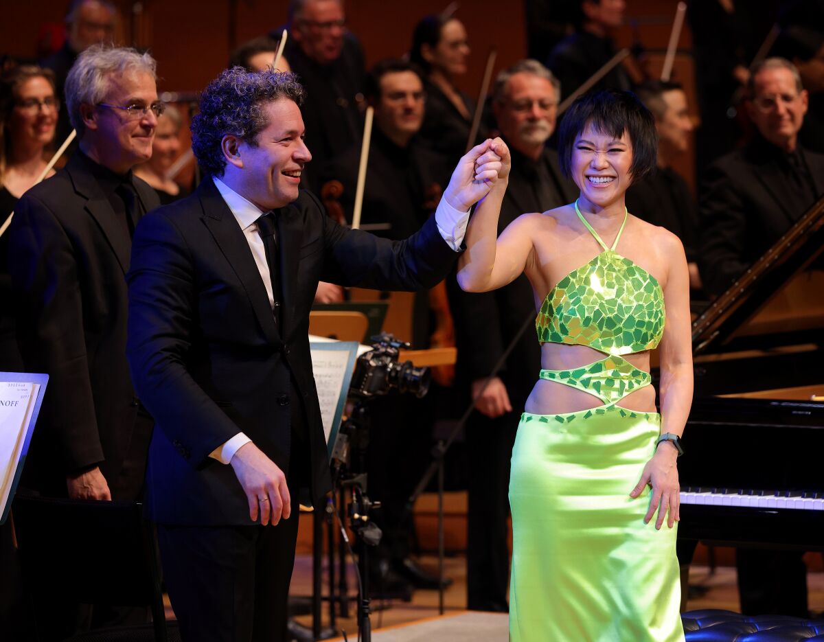 Yuja Wang and Gustavo Dudamel raise grasped hands as they acknowledge applause.
