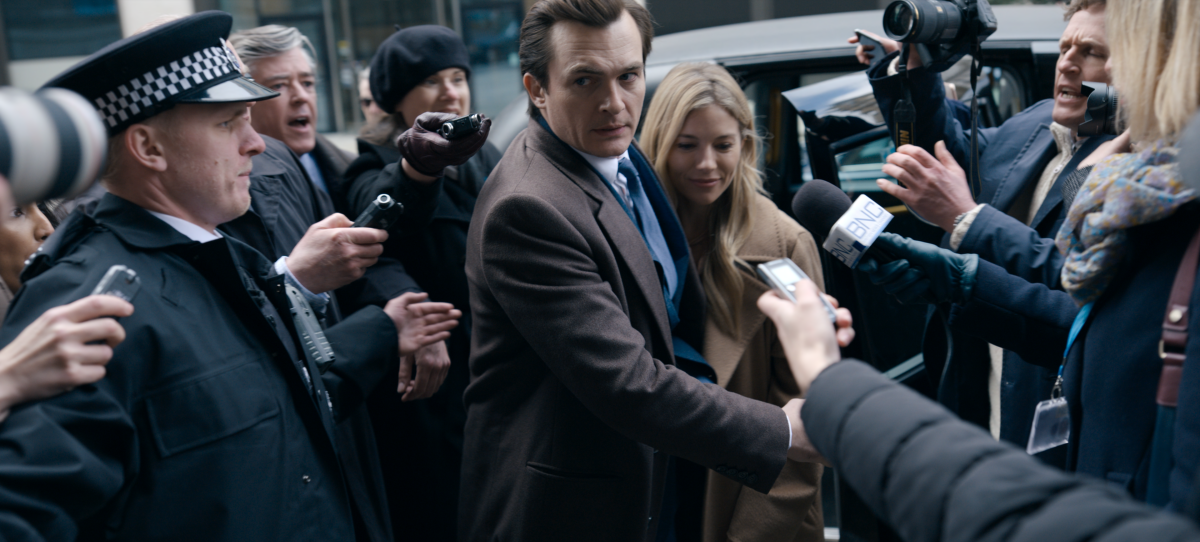In "Anatomy of a Scandal," a man and woman are surrounded by news cameras and microphones.