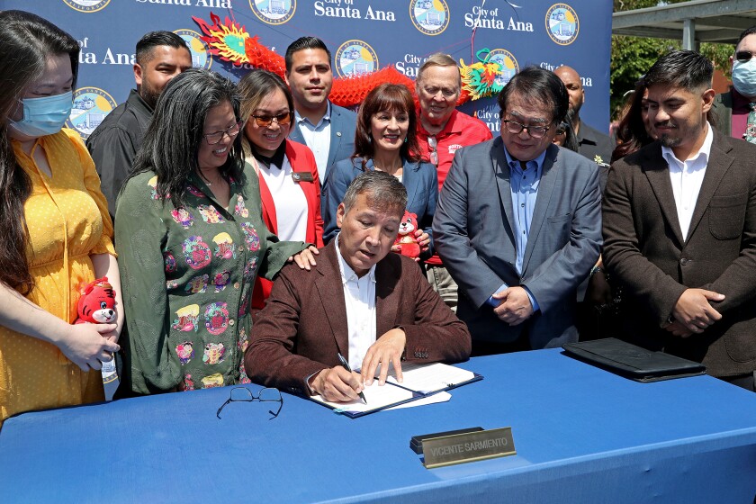 Mayor Vicente Sarmiento signs the Chinatown Apology Resolution during a ceremonial event.