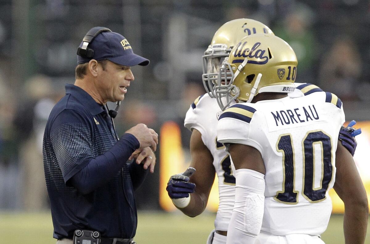 UCLA Coach Jim Mora speaks with players Anthony Jefferson, center, and Fabian Moreau during the first half of a game against Oregon in October. Mora says Moreau is developing into a "sure fire" first-round draft pick.