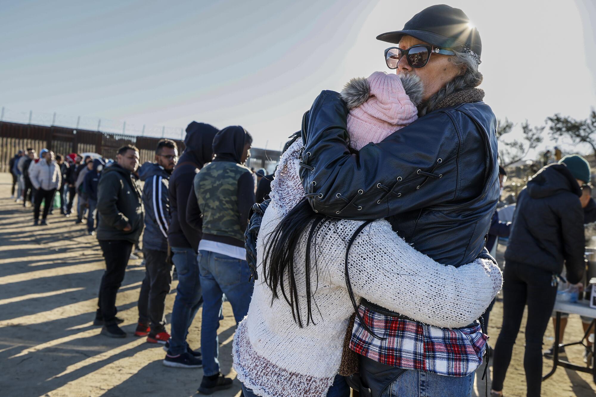 Two women embrace at a migrant camp. 