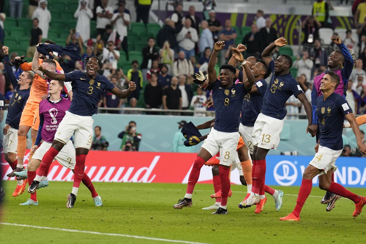 French players jump in the air and raise their arms while running.