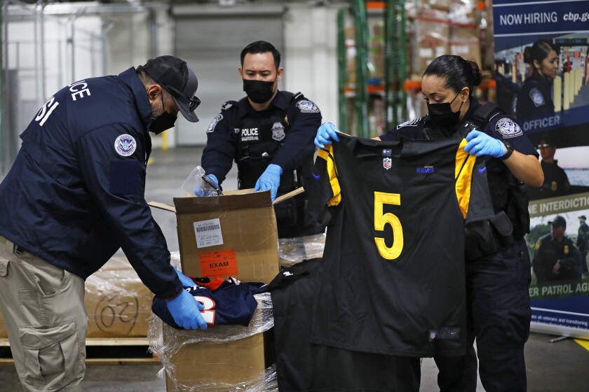 United States Customs and Border Protection officers open boxes of counterfeit goods