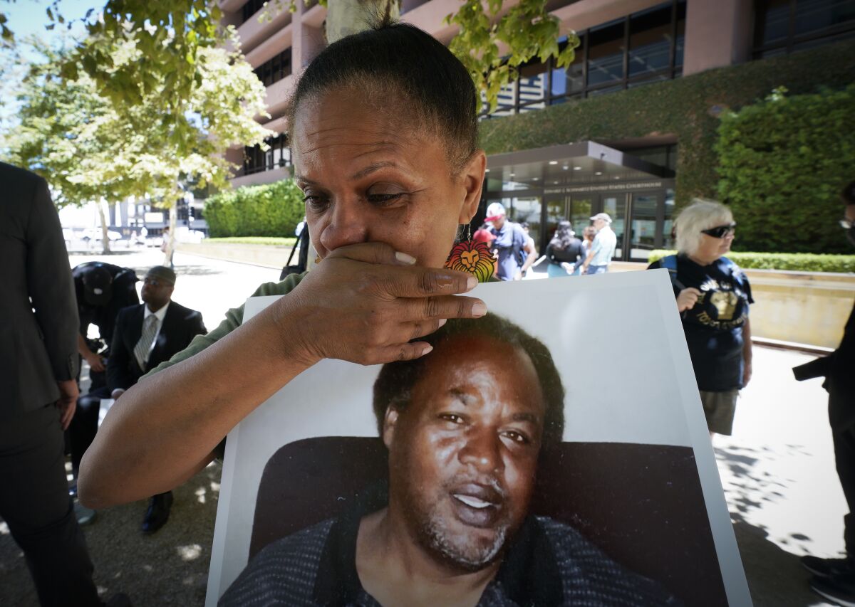 Shawn Mills holds a photo of her brother, Kevin Mills, at a news conference in 2022. Kevin Mills died while in a county jail.