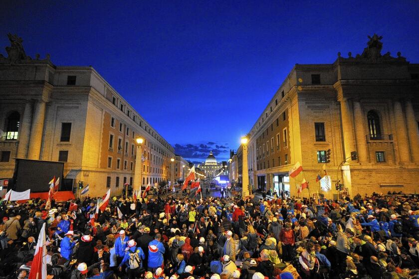 People are gathered on the Via della Conciliazione, which leads to St. Peter's Square on the eve of the canonization of Pope John Paul II and Pope John XXIII.