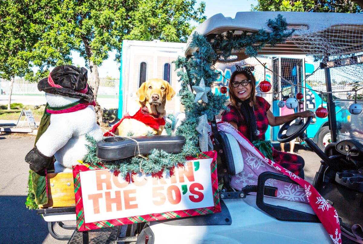 Linda Rosas with her dog, Winnie, in their Pacific Beach Holiday Parade entry with the PB Golf Cart Gang.