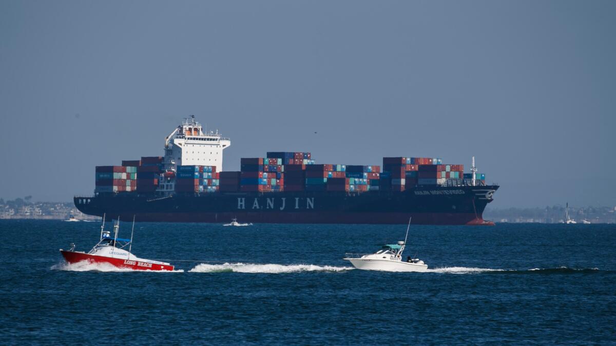 Small vessels pass the Hanjin Montevideo, anchored near the coast of Long Beach, on Sunday.