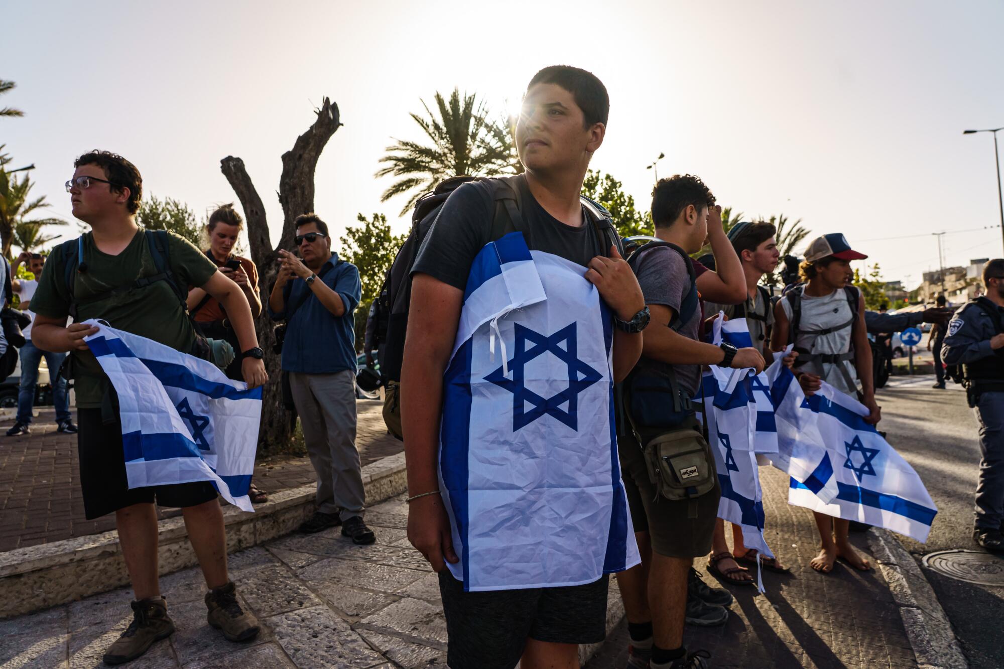 Young men stand in the street holding Israeli flags.