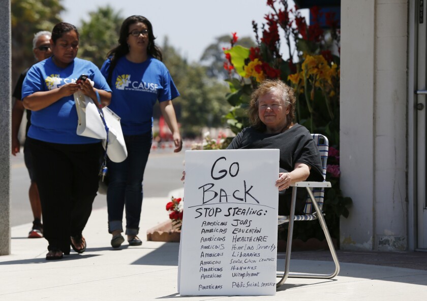 Protester Darlene Mosser sits outside the Naval Base Ventura County in Port Hueneme on Tuesday, when religious, community and legislative leaders toured the facility holding hundreds of unaccompanied minor detainees.