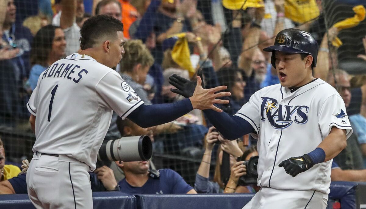 Tampa Bay Rays first baseman Ji-Man Choi (26), right, celebrates scoring along with shortstop Willy Adames (1) after Choi scored on a single in the first inning against the Houston Astros in Game 4 of the ALDS on Tuesday in St. Petersburg, Fla.