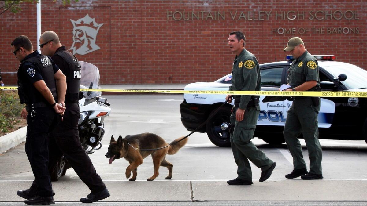 In this 2014 file photo, an Orange County Sheriff's Deparment dog investigates the campus at Fountain Valley High School after a bomb threat. A Sheriff's Department patrol canine attacked a county employee inside his office last week.