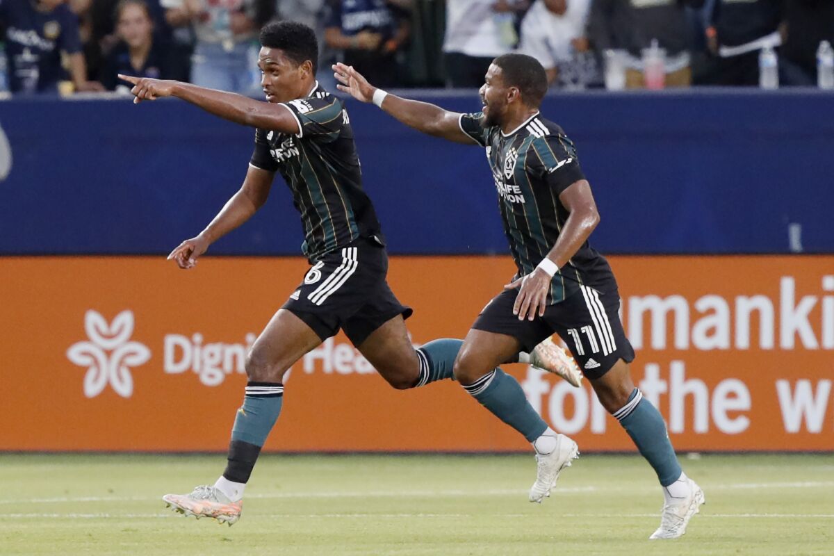 LA Galaxy's Rayan Raveloson leaps in the air with a teammate to celebrate a goal. 