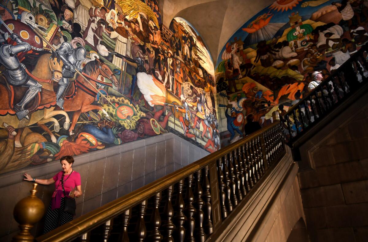 A woman walks by a huge mural painted by famous Mexican artist Diego Rivera inside the National Palace in Mexico City.