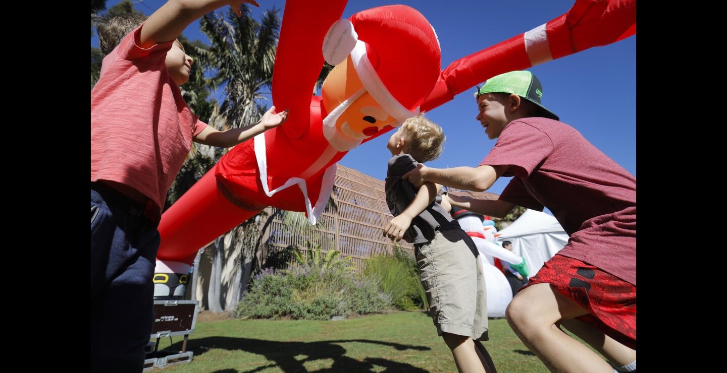 Brothers, Five-year-old Arie Van Riet, left, and eight-year-old Ryker Van Riet, right, of Carlsbad, get up close with an inflatable Santa Claus air dancer in front of the The Botanical Building in Balboa Park during the second day of December Nights.