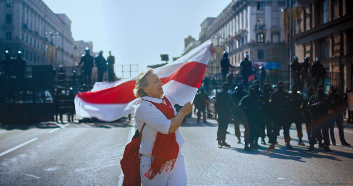A woman unfurls a flag in the middle of the street in the documentary “Courage”