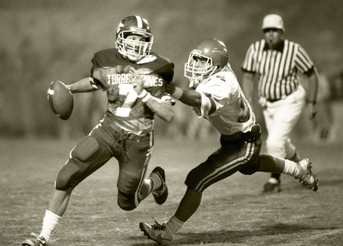 Torrey Pines quarterback John Lynch is pursued by Mt. Carmel defender Pete Wessel in a 1987 game.