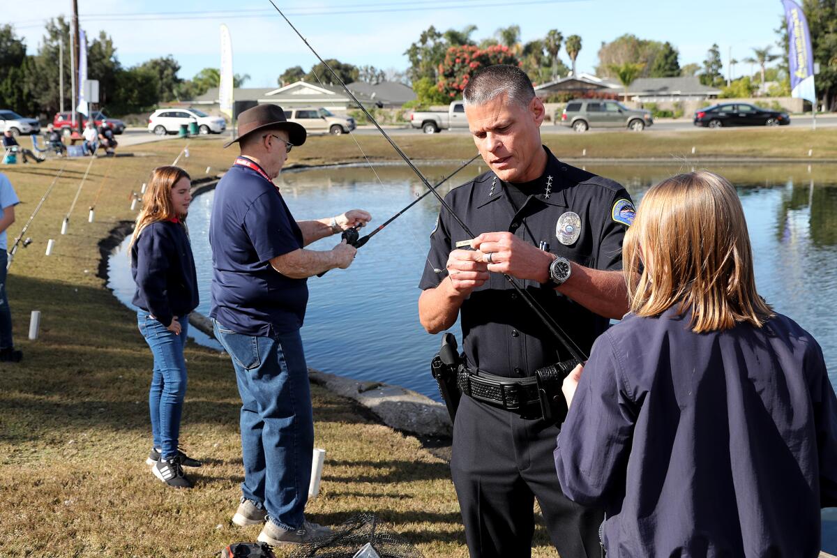 HBPD Chief Eric Parra, second from right, helps Natalie Beavers, far right, attach bait to her fishing line.