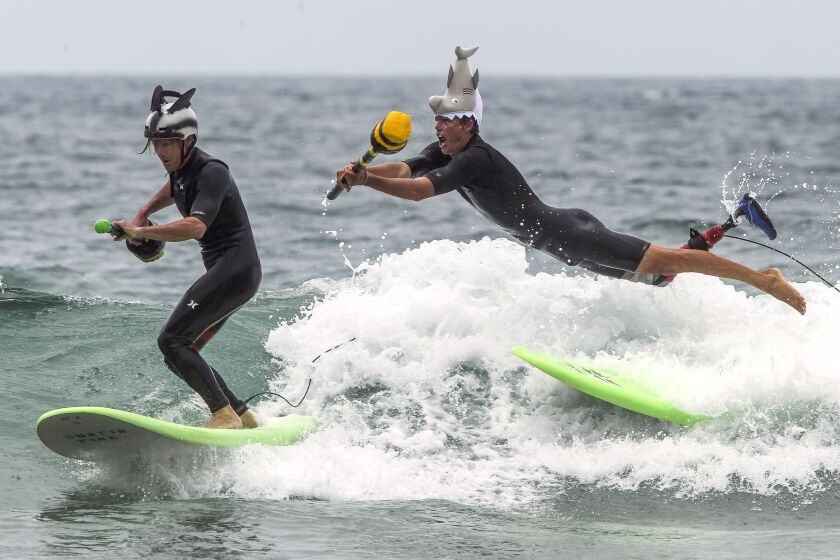 Mike Coots leaps from his surfboard in an attempt to knock Switchfoot band member Jon Foreman off his board as they compete in the surf joust during the Switchfoot Bro-Am music and surf festival at Moonlight Beach on Saturday, June 29, 2019 in Encinitas, California.