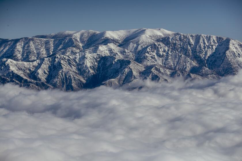 SAN BERNARDINO, CA - APRIL 03: Snow-covered peaks of the San Bernardino Mountains rise above the clouds on Monday, April 3, 2023 in San Bernardino, CA. (Brian van der Brug / Los Angeles Times)