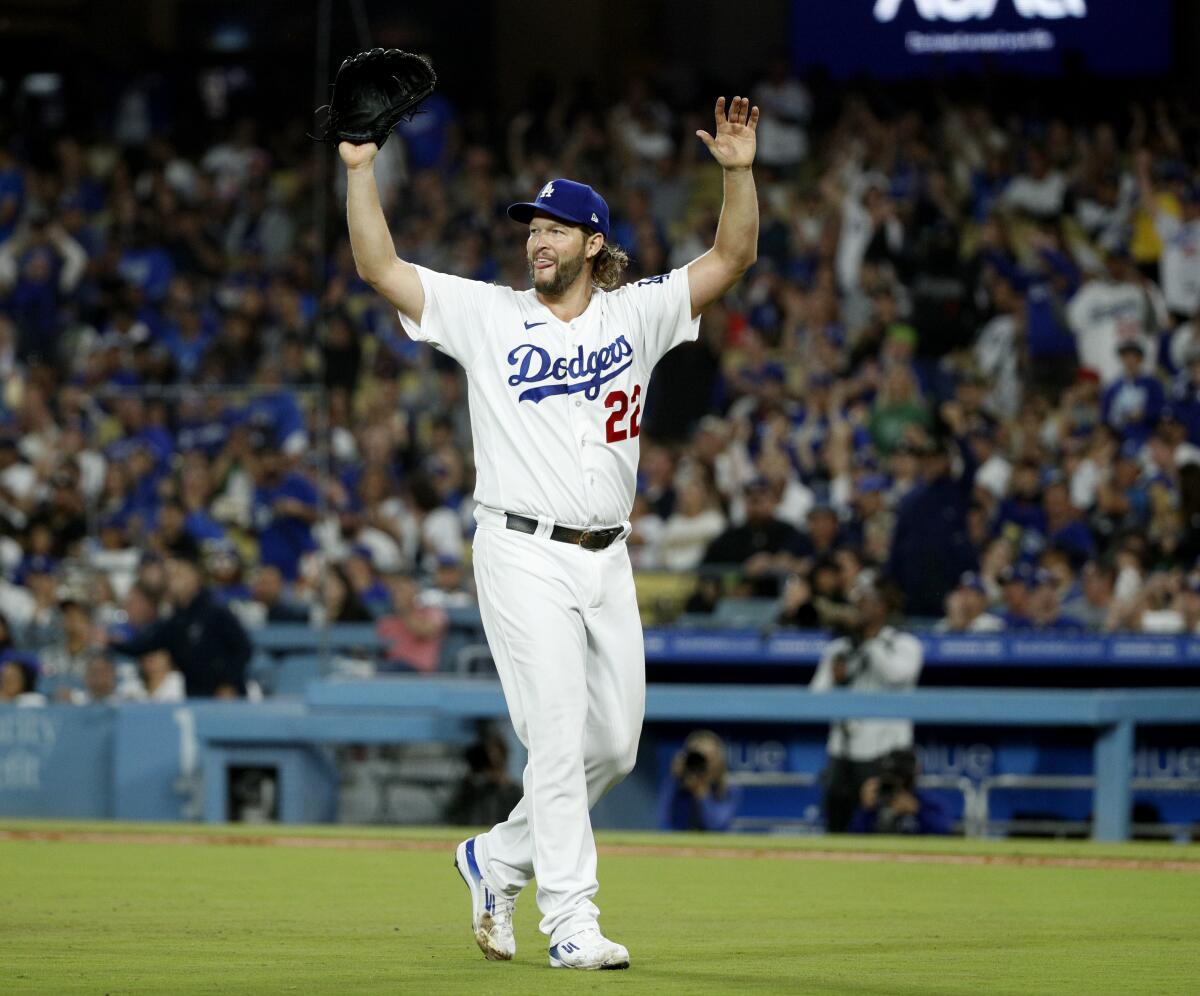 Dodgers pitcher Clayton Kershaw raises his arms in celebration on the baseball field.