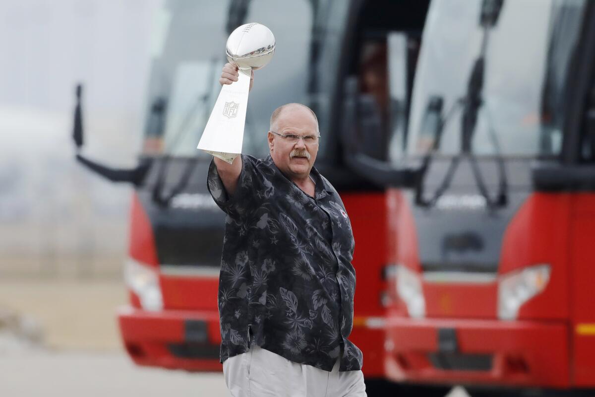 Sporting a Hawaiian shirt, coach Andy Reid hoists the Vince Lombardi Trophy after the Super Bowl champion Chiefs landed in Kansas City.
