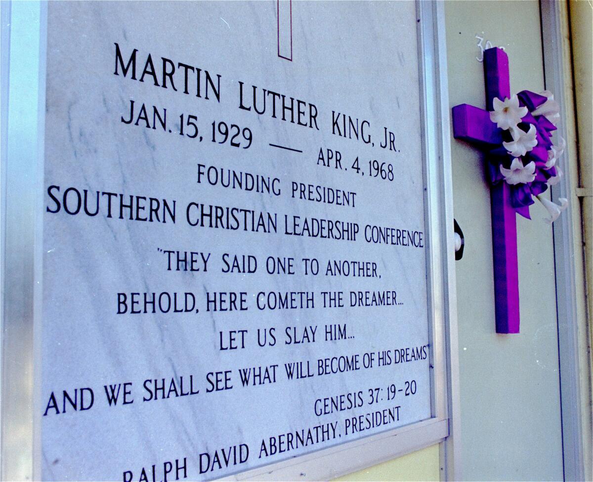A plaque, next to a purple cross on a door, reads in part: "Martin Luther King, Jr.: Jan. 15, 1929 - April 4, 1968."