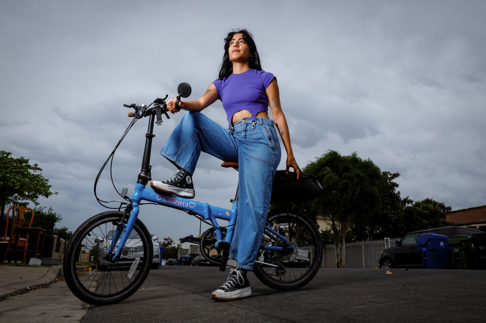 A portrait of Michelle Moro on a neighborhood street with her blue bike.