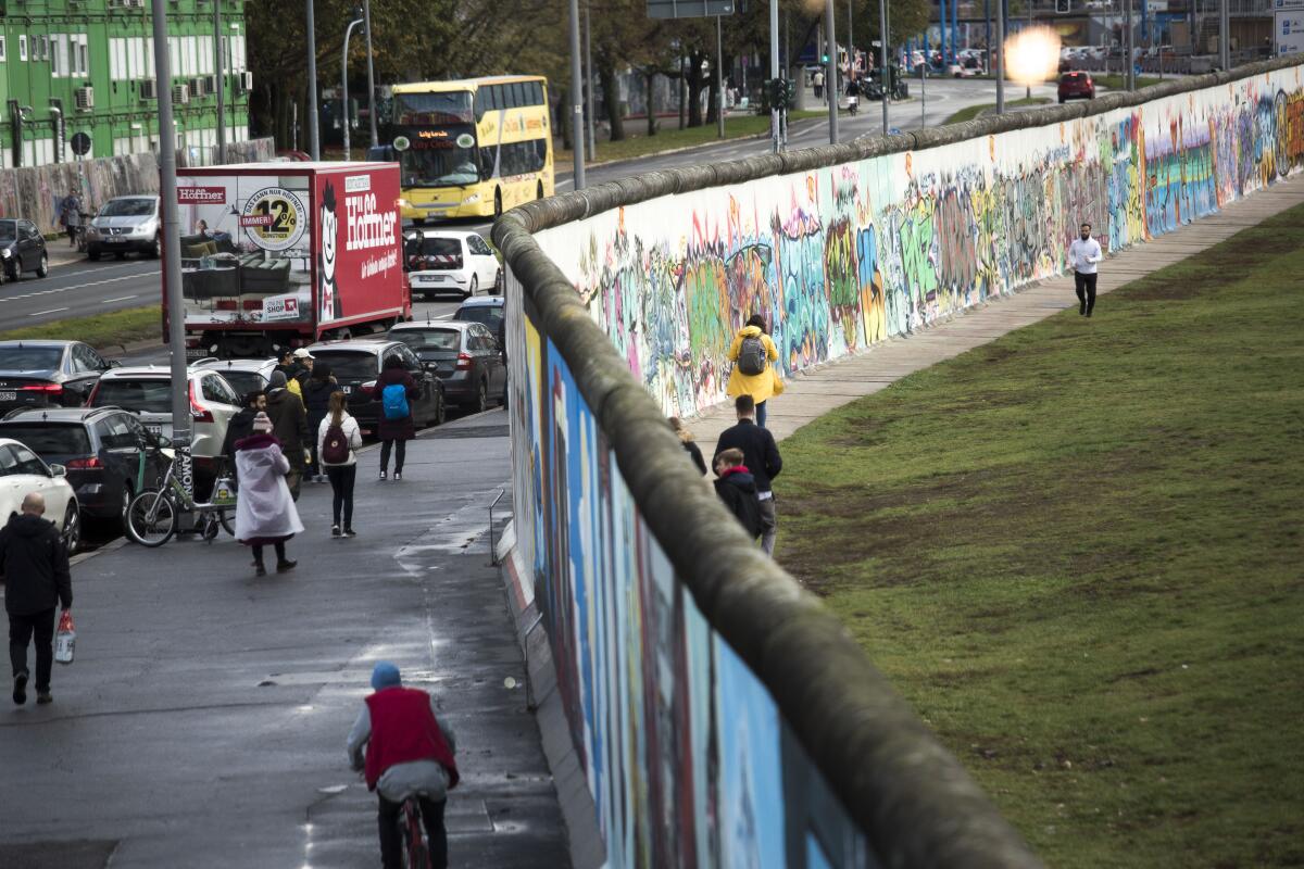 Tourists walk at a former section of the Berlin Wall called the East Side Gallery on the first day of events celebrating the 30th anniversary of the fall of the Berlin Wall in Berlin, Germany.