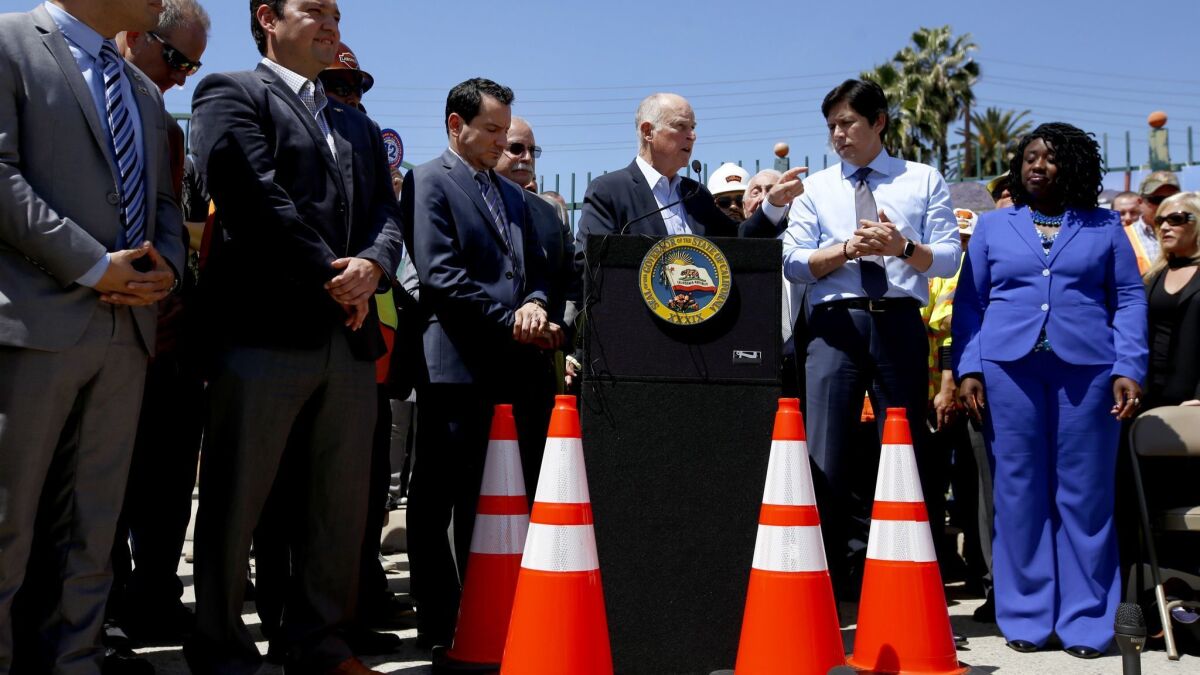 Assembly Speaker Anthony Rendon, left, Gov. Jerry Brown and then-Senate President pro Tem Kevin de León take part in a 2017 rally for a bill that raised the gas tax.