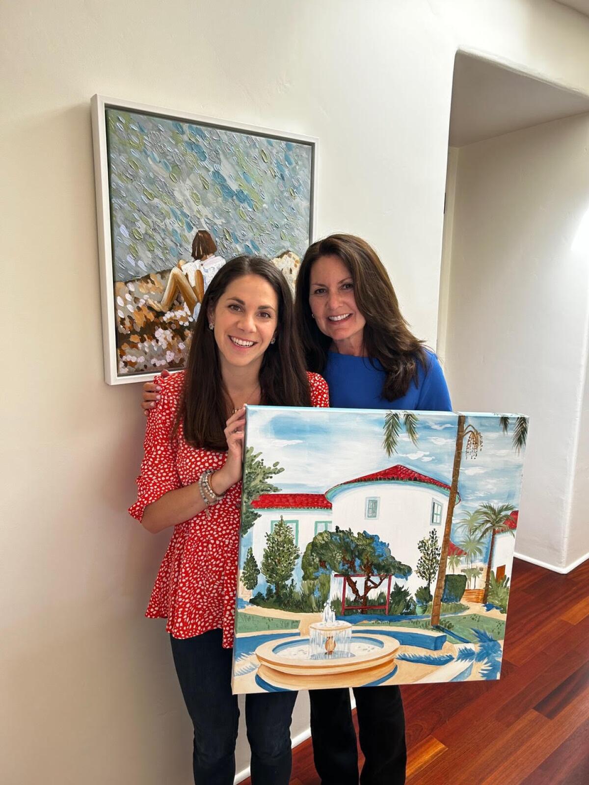 Artist Diane Lehman and Lisa Danaher hold one of Lehman’s paintings in front of a canvas print Lehman modified for Danaher.