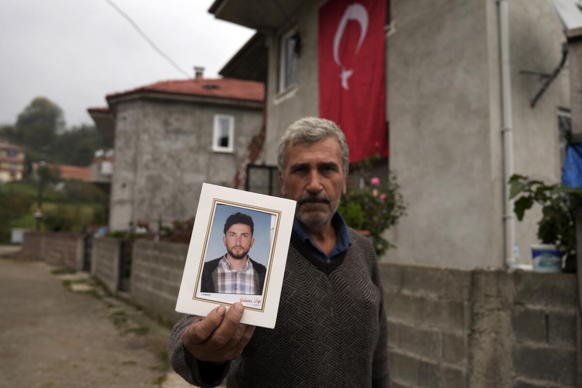 Recep Ayvaz, 62, shows a picture of his son, Selcuk Ayvas, 33, one of the miners killed in a coal mine explosion, in front of his house in Amasra, in the Black Sea coastal province of Bartin, Turkey, Sunday, Oct. 16, 2022. (AP Photo/Khalil Hamra)