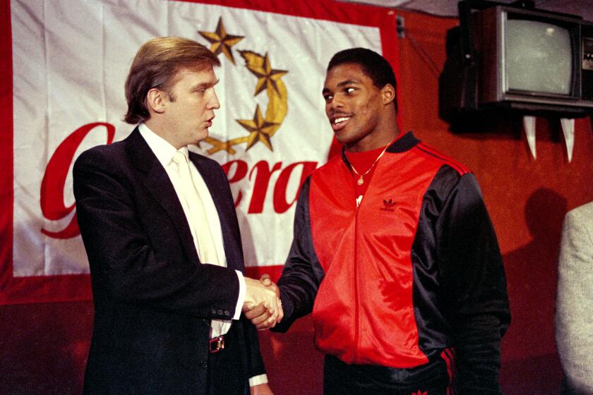 FILE - In this March 8, 1984, file photo, then-New Jersey Generals owner Donald Trump, left, shakes hands with Herschel Walker at a press conference in New York, after agreeing on a 4-year contract. Retired NFL player Herschel Walker says he's being dropped from speaking engagements because of his relationship with Donald Trump. (AP Photo/Dave Pickoff, File)