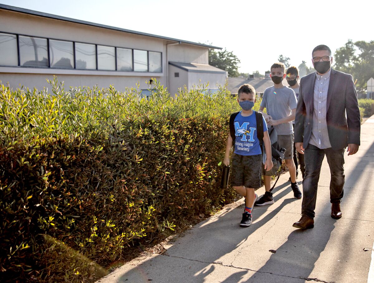 Lemon Grove school board member Javier Ayala walks his children to school at Lemon Grove on Thursday.
