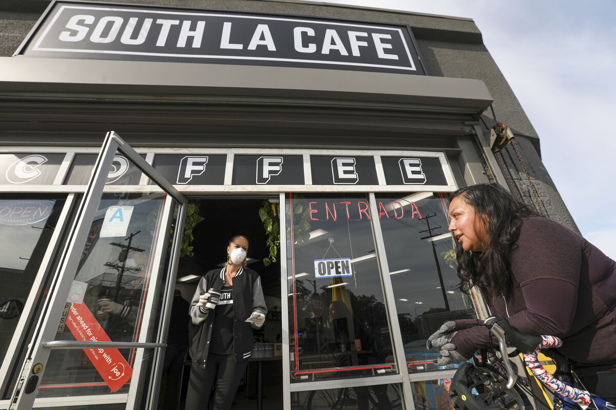 Celia Ward-Wallace, left, brings a takeout order to Sandra Flores at South LA Cafe